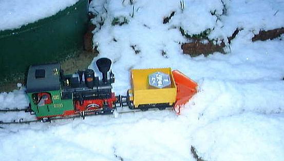LGB-Lok Stainz mit zum Schneepflug umgebauten Feldbahn-Kastenwagen bei ersten Schneerumversuchen im frischen Neuschnee