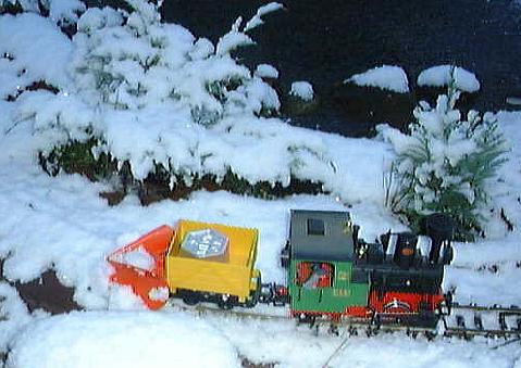 LGB-Lok Stainz mit zum Schneepflug umgebauten Feldbahn-Kastenwagen bei ersten Schneerumversuchen im frischen Neuschnee